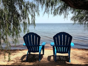 Two blue Adirondack chairs facing a body of water with a tree overhead. - Escape to a Scenic Lakeview Cabin Near Waterfalls, Vineyards & Starry Nights in Buchanan Dam, Texas (Buchanan Dam)