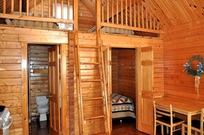 L’intérieur d’une cabane en bois comprend une salle de bain, une petite chambre avec un lit et un coin repas.