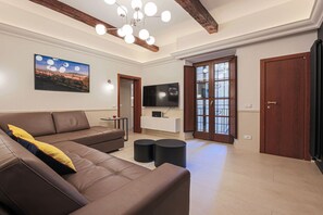 Ein Wohnzimmer mit braunem Ledersofa, einem Fernseher, einem weißen Schrank und einem großen Fenster mit Blick.