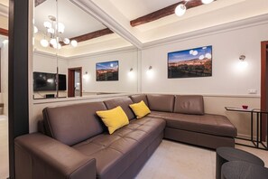 A modern living room with a brown leather sectional sofa, two yellow cushions, a large mirror, and framed pictures on the wall. - Apartments Florence - Charming Sant'Egidio (Florence)