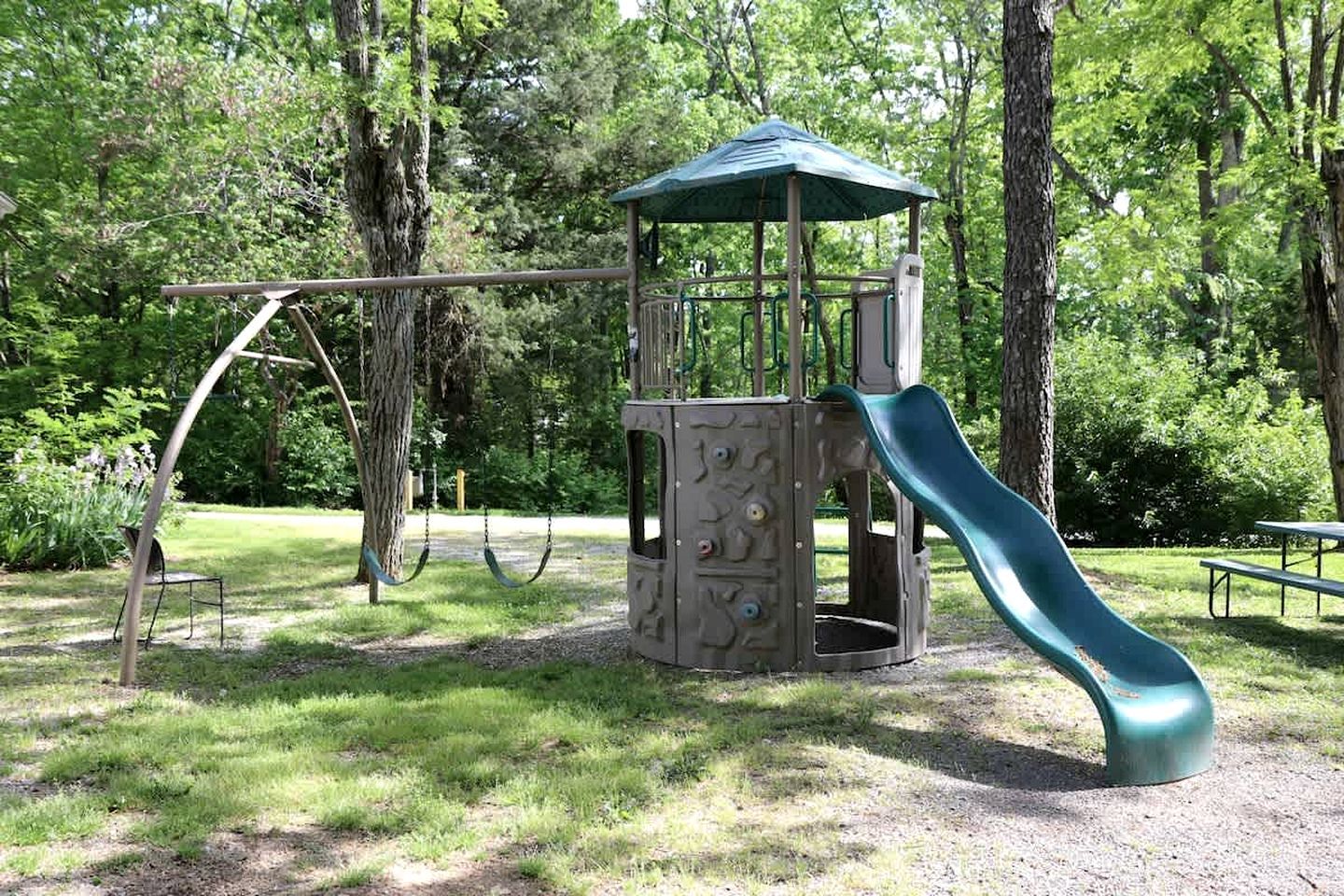 Un parque infantil con tobogán, columpios y una estructura de juegos cubierta.