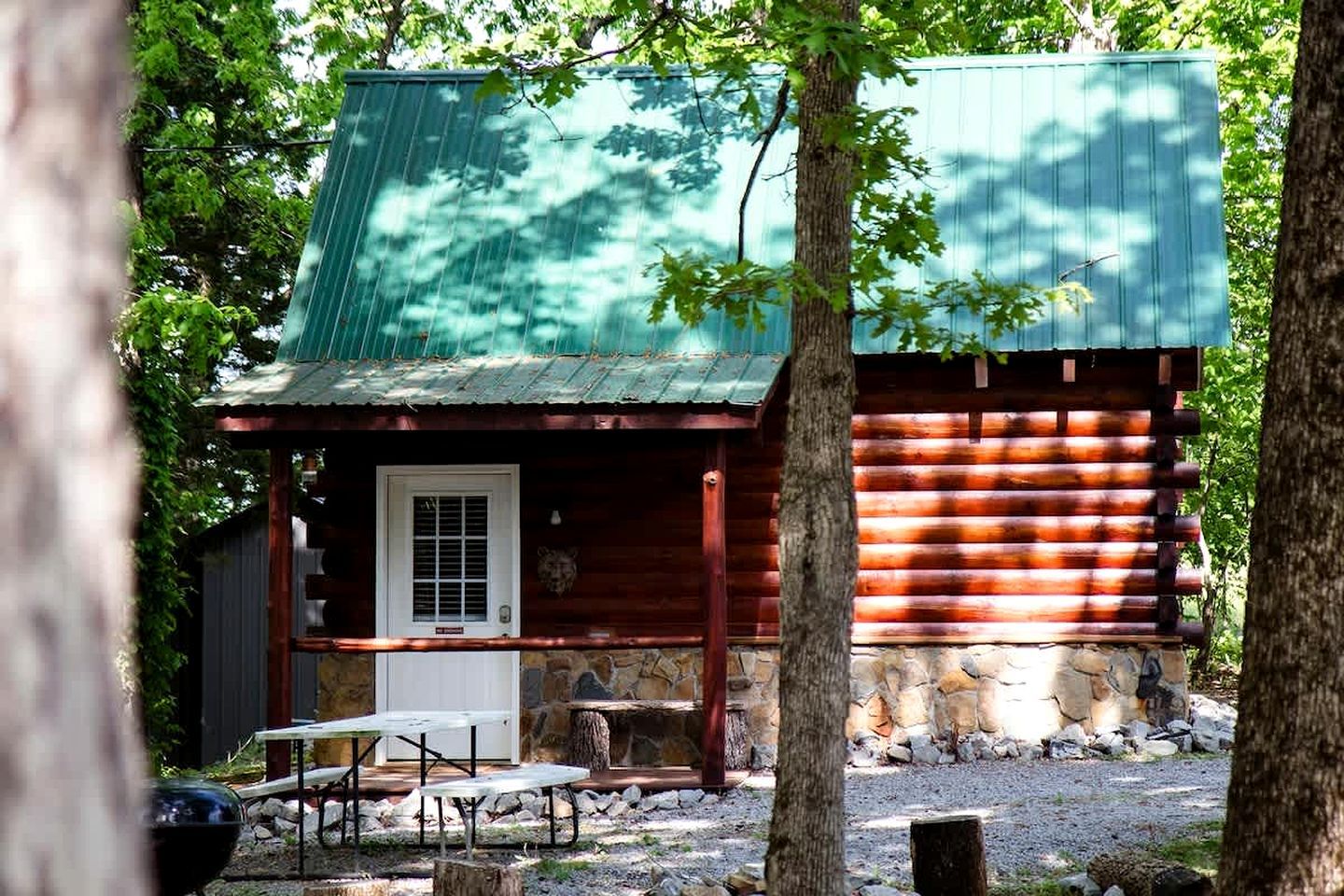 A rustic cabin with a stone foundation, a wooden exterior, and a metal roof.