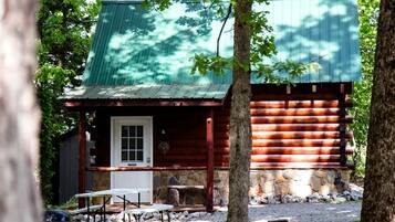A rustic cabin with a stone foundation, a wooden exterior, and a metal roof.