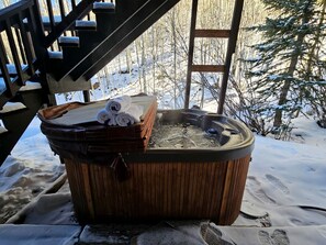 A hot tub with towels and a bag, surrounded by snow and a wooden deck. - Beautiful Vacation Rental with Creek Running Through the Property for a Relaxing Getaway in Nature in Breckenridge, Colorado (Breckenridge)