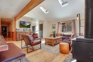 A spacious living area with a fireplace, wooden furniture, and a view of the outdoors. - Beautiful Vacation Rental with Creek Running Through the Property for a Relaxing Getaway in Nature in Breckenridge, Colorado (Breckenridge)
