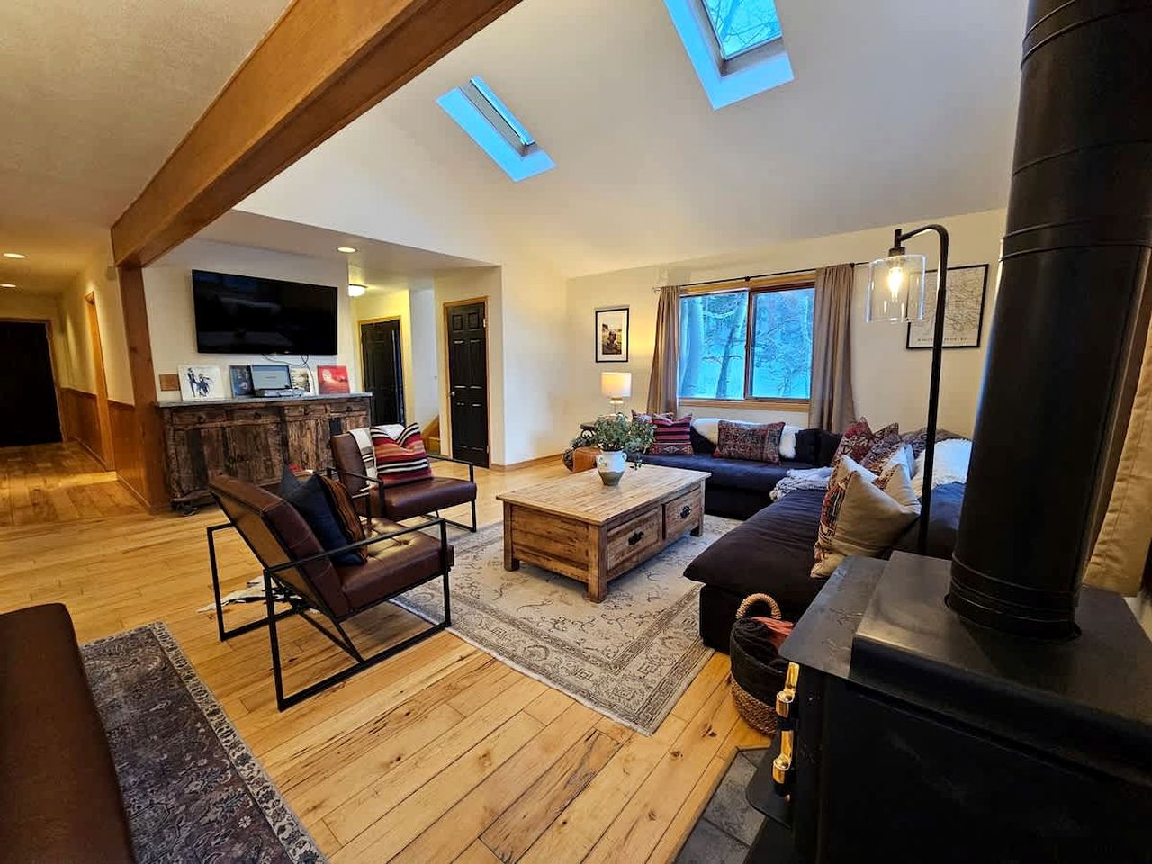 A spacious living room with a fireplace, wooden flooring, a sofa, a coffee table, and a television.