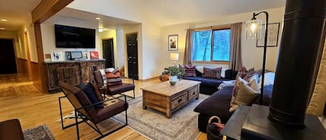 A spacious living room with a fireplace, wooden flooring, a sofa, a coffee table, and a television.