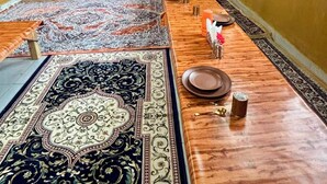 A long dining table with multiple chairs, a wooden ceiling, and a large rug.