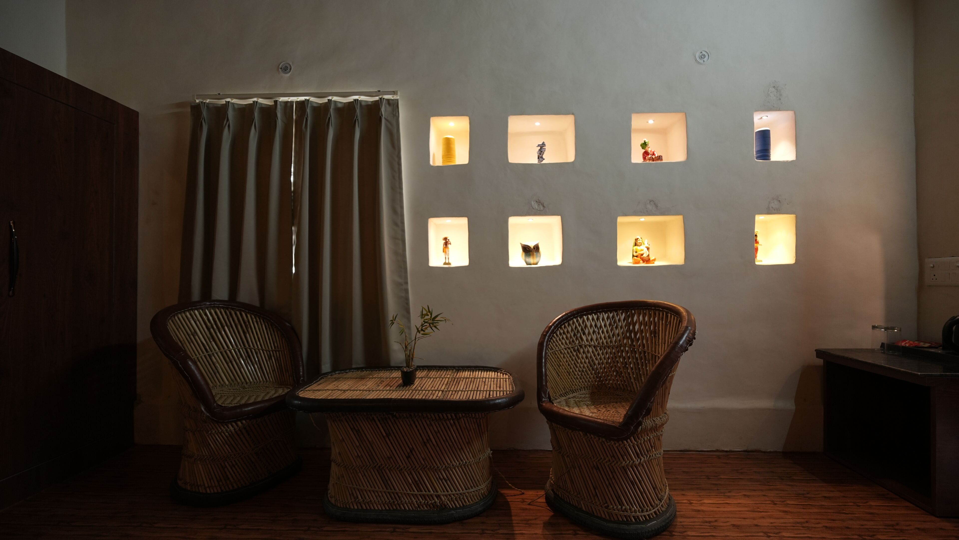 Une pièce comprenant deux fauteuils en osier, une petite table, un rideau et des luminaires fixés au mur, agrémentés de divers objets décoratifs.