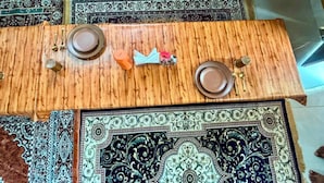 A dining table with plates, cutlery, and a decorative item. - Vrinda Tapovan Farmstay (Chhata)