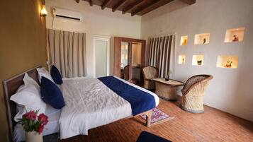 A bedroom with a bed, a chair, a small table, and a mirror.