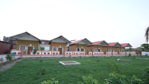 A row of yellow buildings with red roofs, white trim, and a central courtyard with grass and planters.