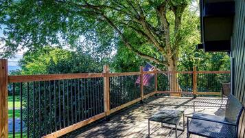 A wooden deck with a metal railing, a bench, and a flag.