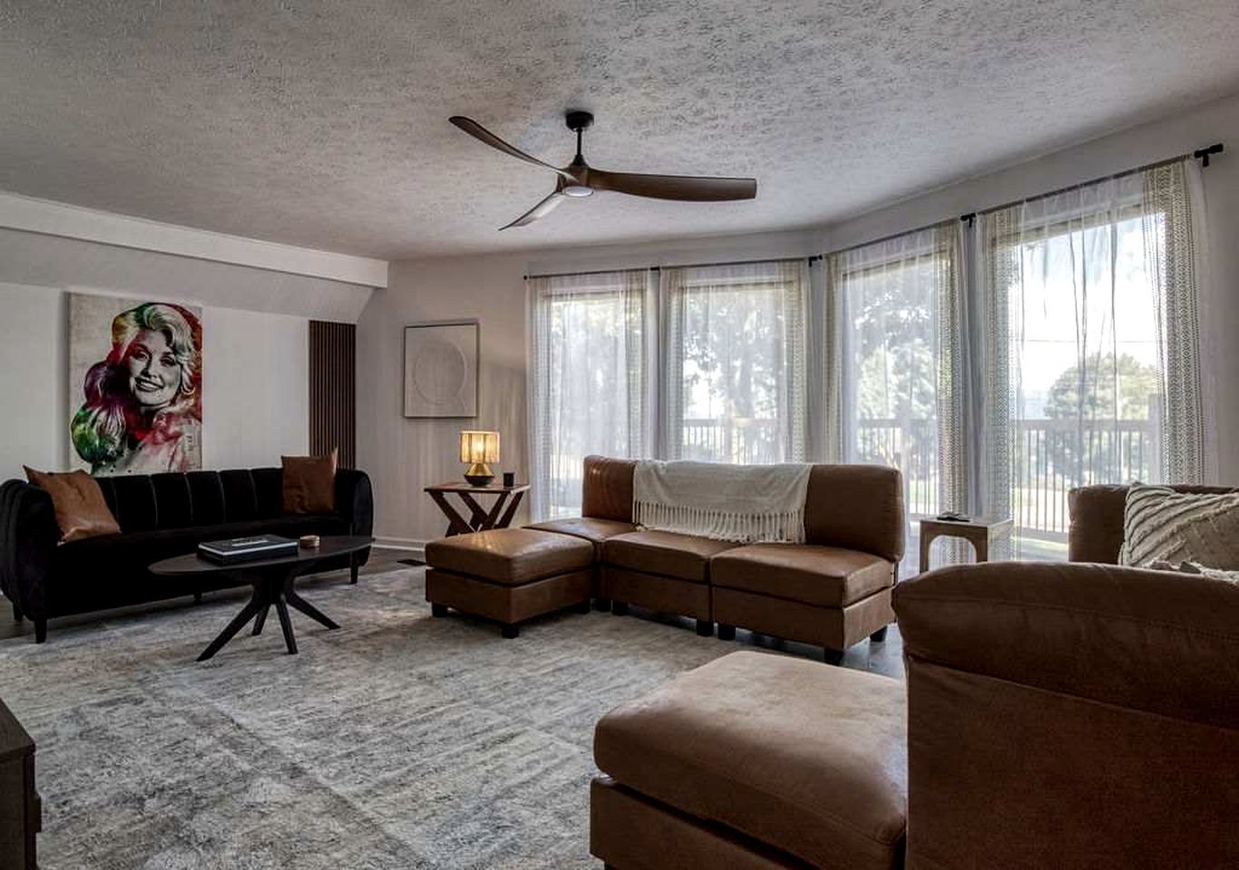 A living room with a sectional sofa, a coffee table, a floor lamp, and a ceiling fan.