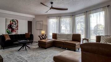 A living room with a sectional sofa, a coffee table, a floor lamp, and a ceiling fan.