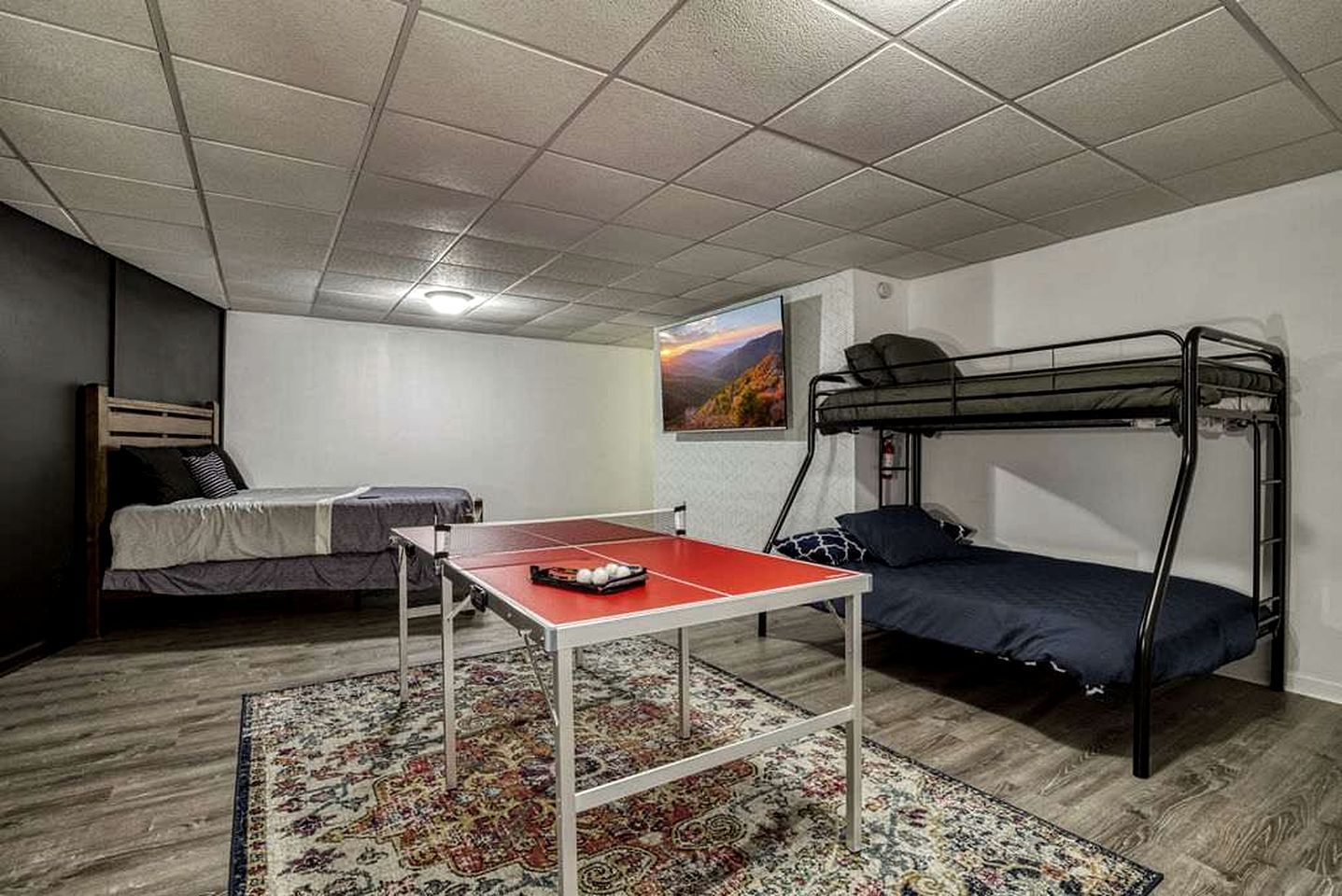 Ein Schlafsaalzimmer mit Stockbetten, einem Tischtennisch und einem gemusterten Teppich.