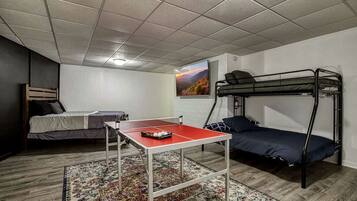 Ein Schlafsaalzimmer mit Stockbetten, einem Tischtennisch und einem gemusterten Teppich.