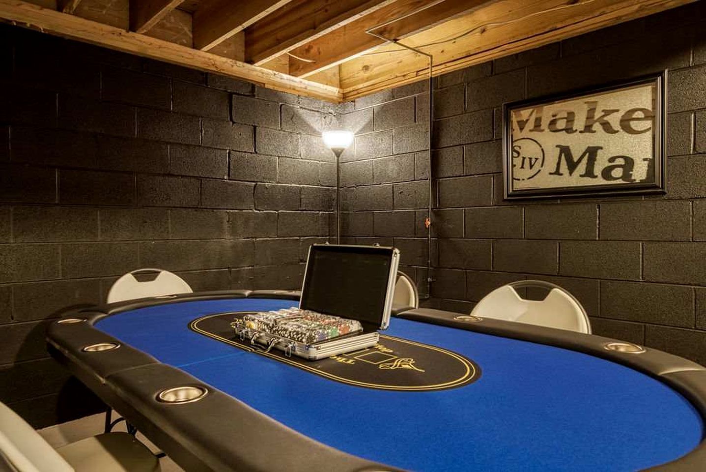 Ein Pokertisch mit Stühlen, ein Laptop und ein gerahmtes Schild an der Wand.