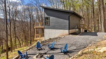 Une cabane dotée d’un patio en gravier, de quatre chaises Adirondack et d’une terrasse en bois.