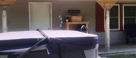 Un espacio al aire libre techado con un banco, una mesa con objetos y un cartel.