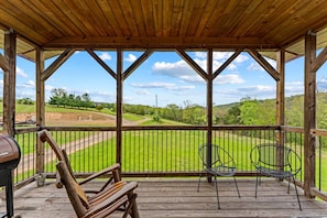 A wooden deck with a view of a green field and a clear sky. - Rustic Mountain Barn Retreat with Private Hot Tub Near Lost River State Park in Wardensville, West Virginia (Wardensville)