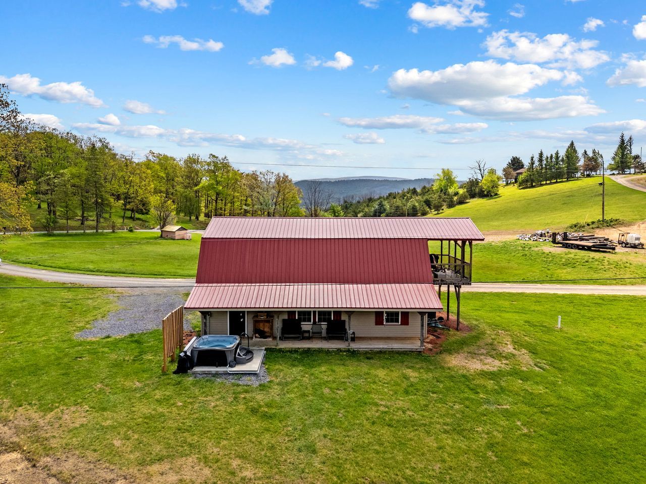 A single-story building with a red roof, a covered porch, and a hot tub in the front yard.