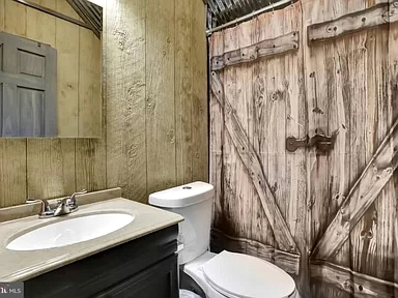 A bathroom with a wooden wall, a sink, and a toilet.