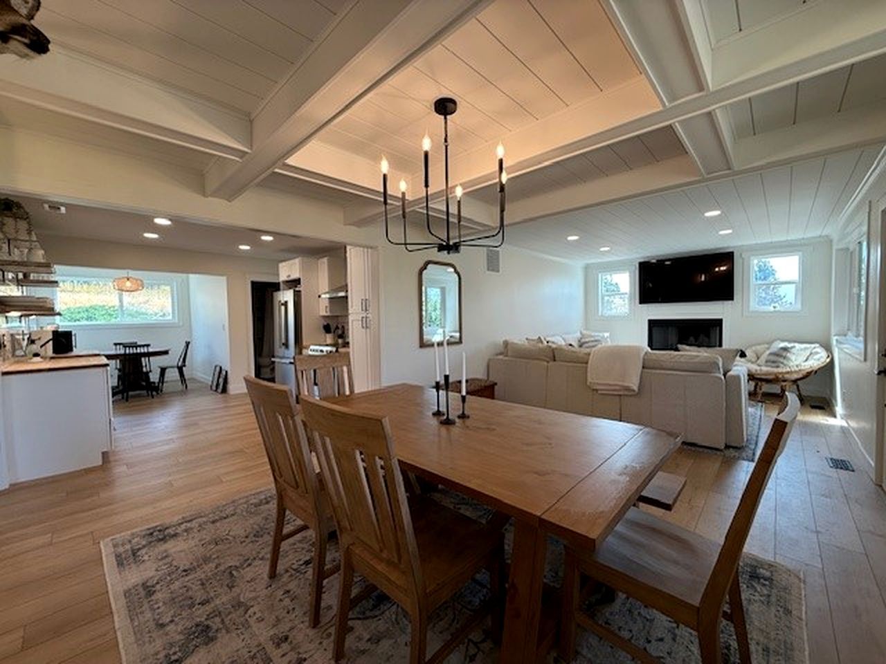 A spacious living area with a wooden dining table, a sofa, and a television.
