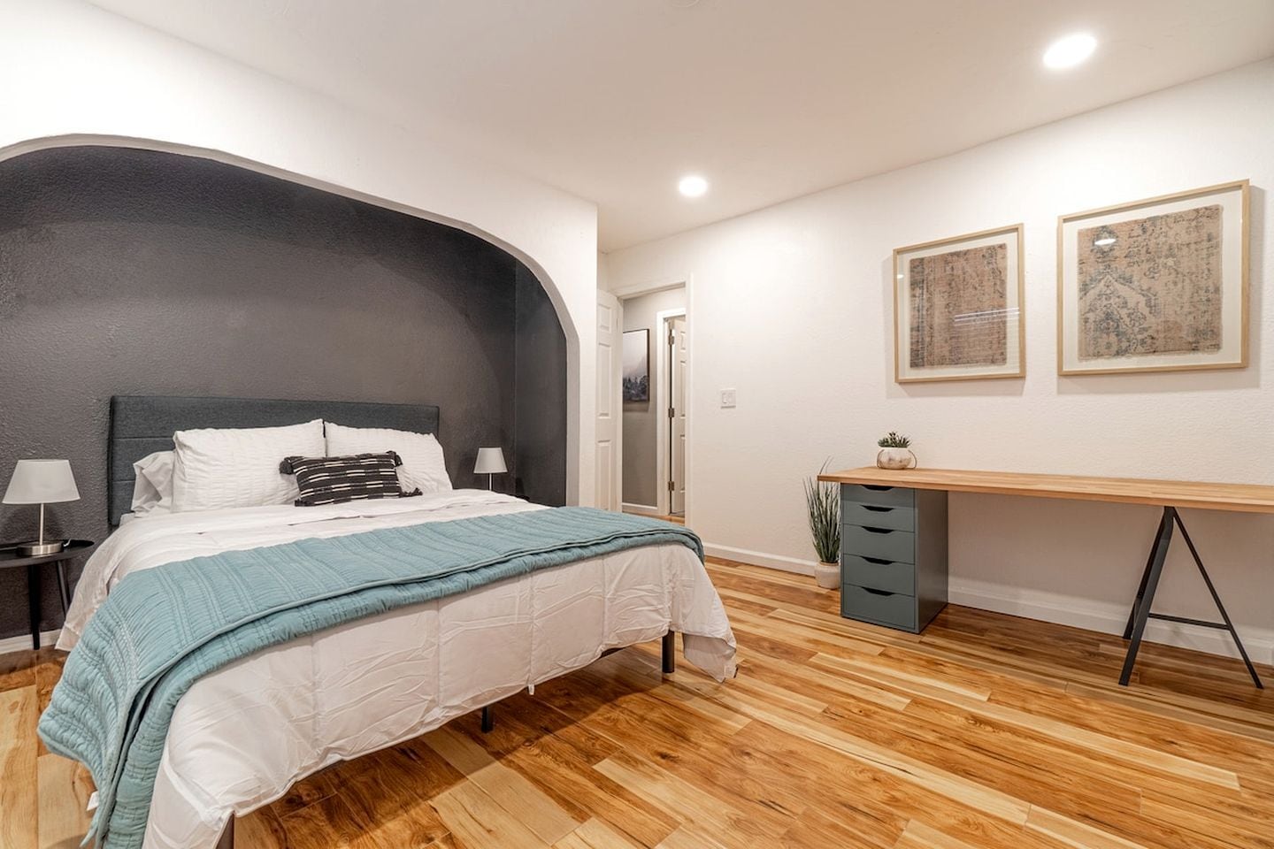 A bedroom with a bed, bedside tables, a desk, and a chair.