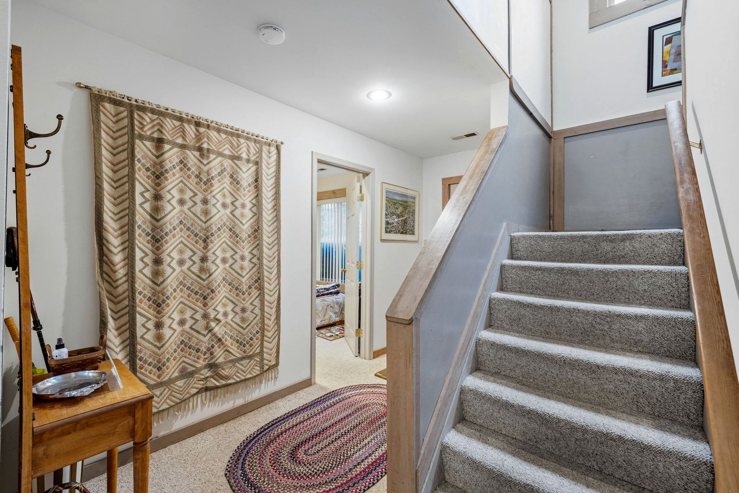 A staircase leading to a bedroom with a patterned curtain and a small table with a tray.