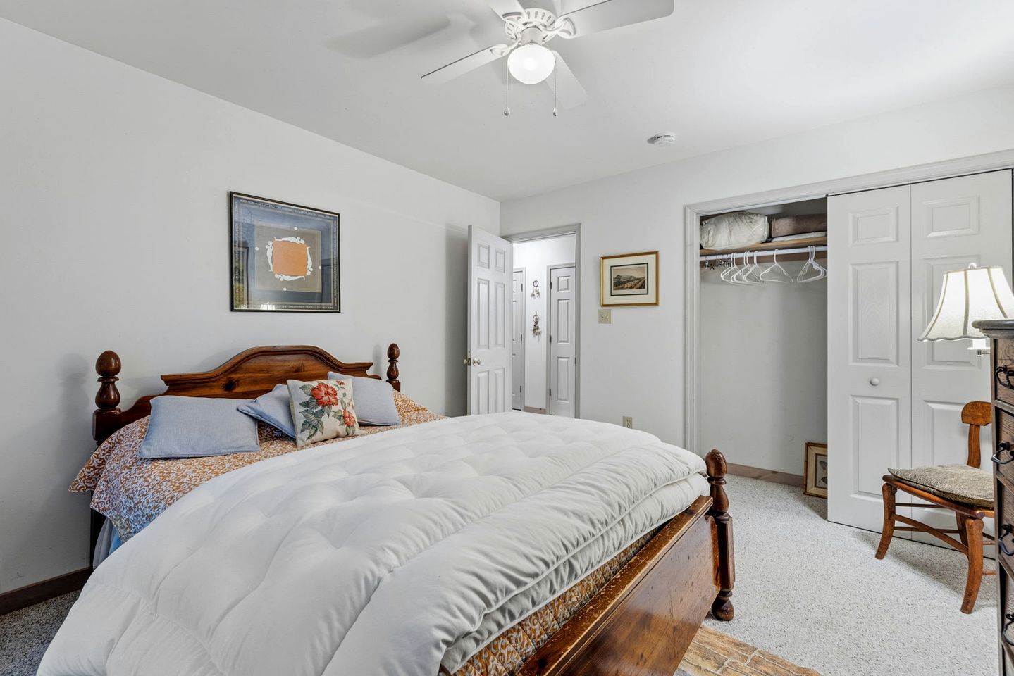 A bedroom with a bed, a ceiling fan, a wardrobe, and a chair.