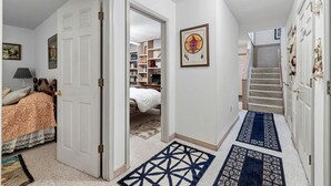 Un corridoio con un letto, una libreria, un quadro incorniciato e una scala.
