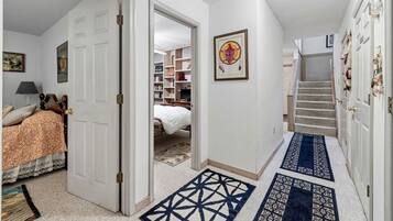 A hallway with a bed, a bookshelf, a framed picture, and a staircase.