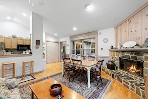 A spacious living room with a fireplace, a dining area with a wooden table and chairs, and a kitchen with wooden cabinets and a microwave. - Family Friendly Shenandoah Cabin with Fire Pit and Game Room in Basye Virginia (Basye)