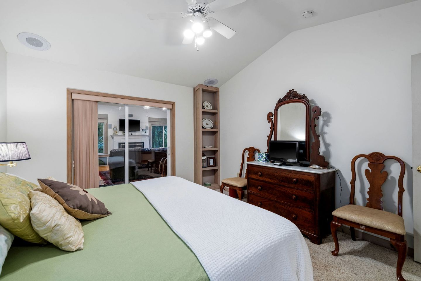 A bedroom with a bed, dresser, chair, and a mirror.