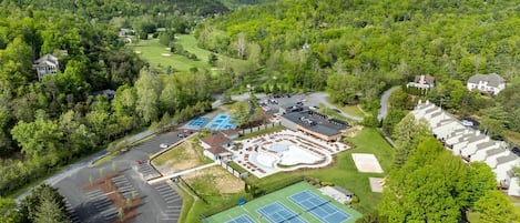 Vue aérienne d’un terrain de golf avec un court de tennis, des aires de stationnement et des immeubles résidentiels.