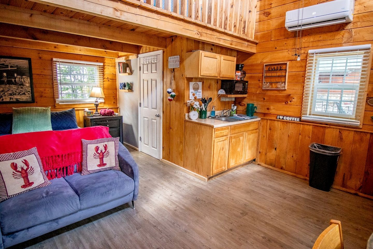 Een gezellig cabinteieur met een bank, een kleine kitchenette en een deur naar een andere kamer.