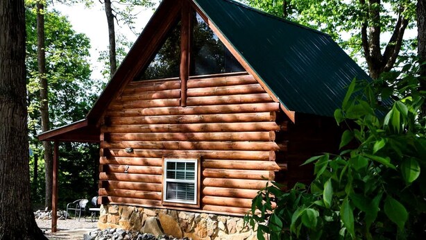 A log cabin with a stone foundation, a window, and a porch. - Cozy Log Cabin Retreat near Green River Lake State Park, Perfect for a Weekend of Fishing (Columbia)