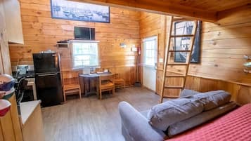 A cabin with a kitchen area, a dining table, and a sofa.