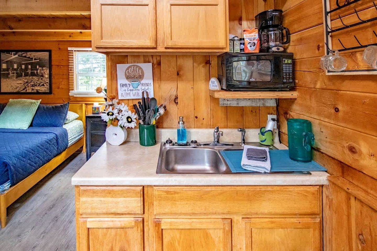 Ein gemütliches Blockhaus-Interieur mit einem Bett und einer Küchenzeile, die Holzausstattung, eine Mikrowelle und eine Kaffeestation bietet.