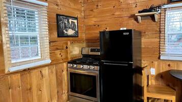Una cocina con paredes de madera, estufa, horno y refrigerador.