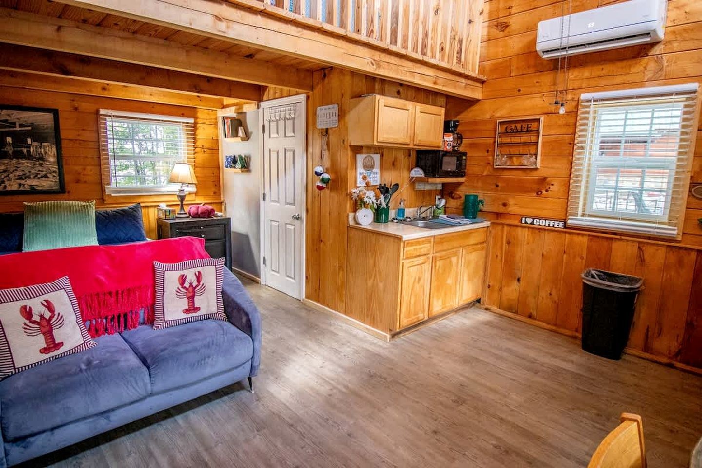 A cozy cabin interior with a sofa, a kitchen area, and wooden walls.