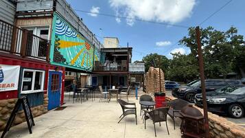 An outdoor seating area with tables and chairs, a blue door, and a colorful mural on the building.