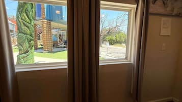 Une pièce avec deux fenêtres, une vue sur l’extérieur et un panneau fixé au mur.