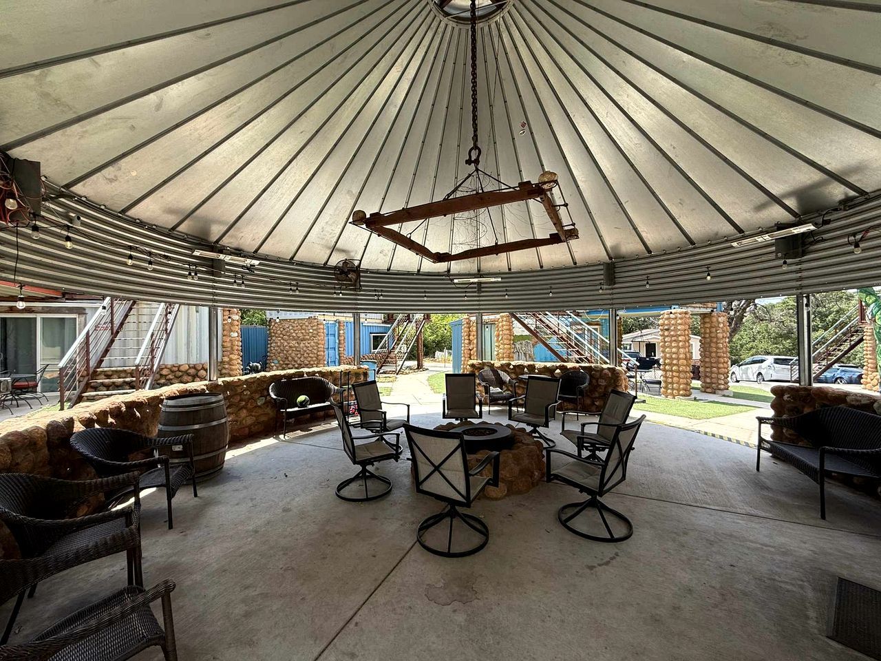 An outdoor patio with a covered seating area, stone walls, and a view of the surrounding buildings.