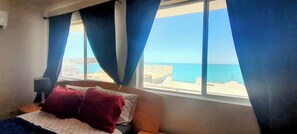 A bedroom with a bed, a nightstand, and a window with curtains.