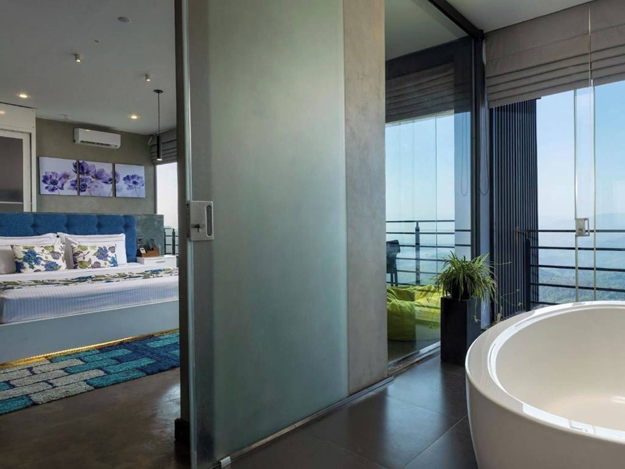 Et moderne soveværelse med en stor seng, et badeværelse med badekar og en balkon med havudsigt.