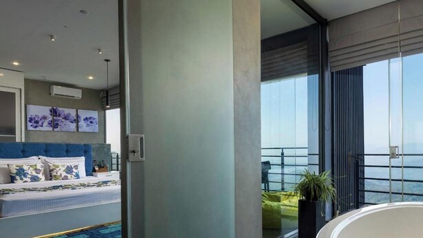 Quarto moderno com uma cama grande, banheiro com banheira e varanda com vista para o mar.