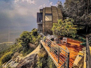 Un edificio moderno con techo curvo, un balcón y una escalera que conduce a una terraza.