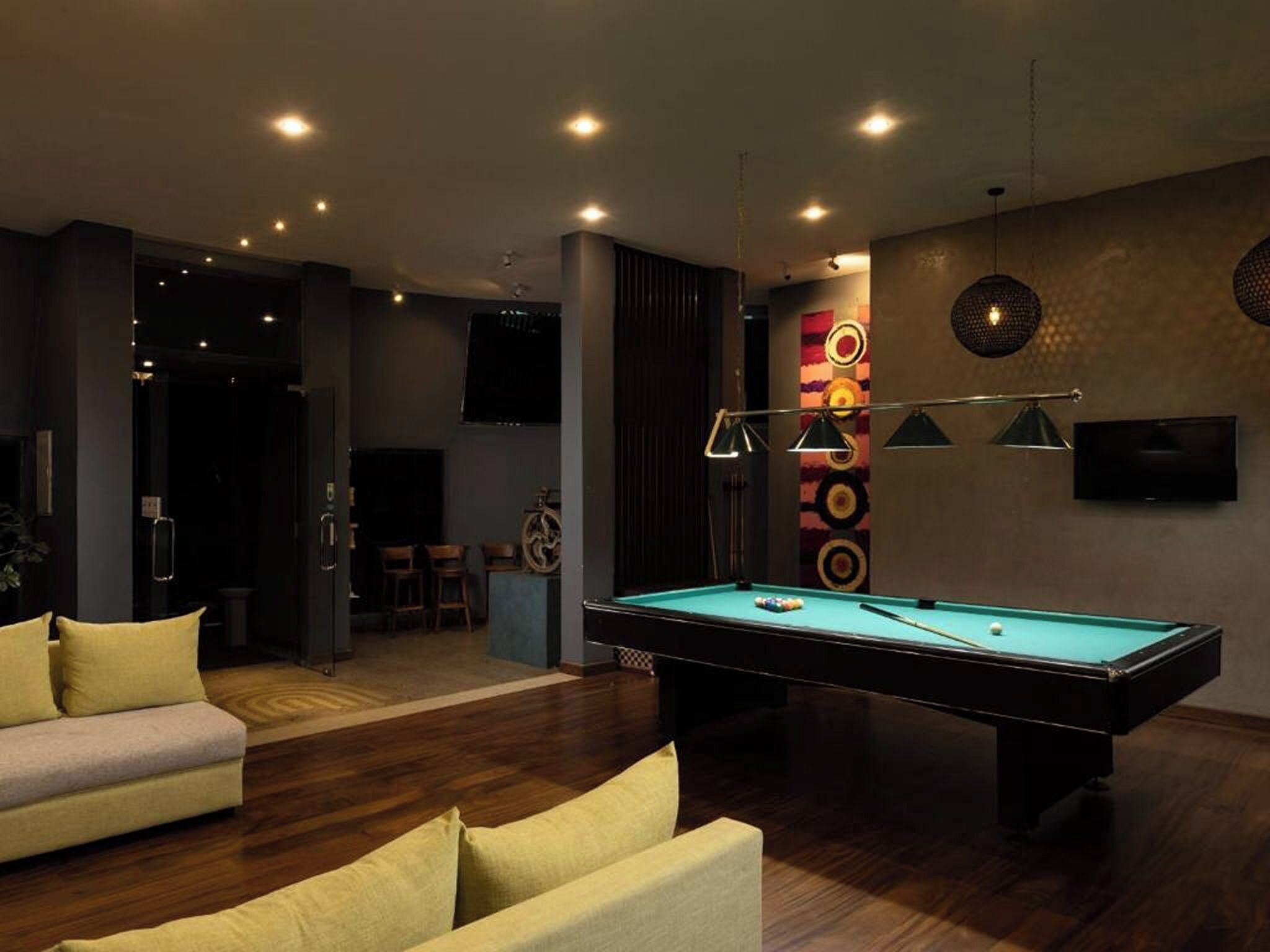 Una sala de estar moderna con mesa de billar, sofás y televisor montado en la pared.